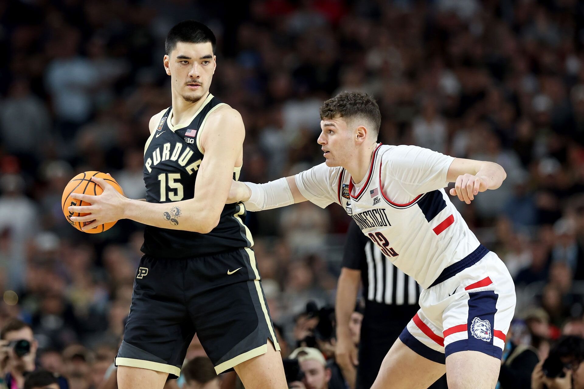 GLENDALE, ARIZONA - APRIL 08: Zach Edey #15 of the Purdue Boilermakers handles the ball while being guarded by Donovan Clingan #32 of the Connecticut Huskies in the first half during the NCAA Men's Basketball Tournament National Championship game at State Farm Stadium on April 08, 2024 in Glendale, Arizona.