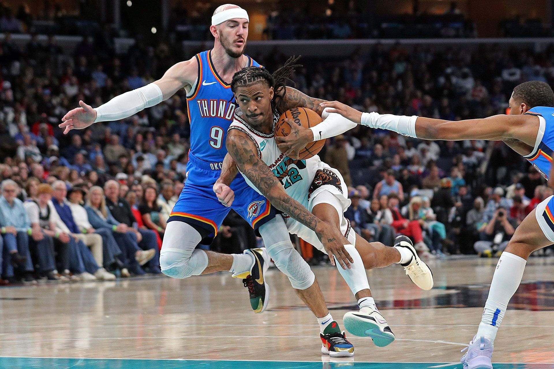 MEMPHIS, TENNESSEE - FEBRUARY 08: Ja Morant #12 of the Memphis Grizzlies goes to the basket between Alex Caruso #9 of the Oklahoma City Thunder and Shai Gilgeous-Alexander #2 of the Oklahoma City Thunder during the first half at FedExForum on February 08, 2025 in Memphis, Tennessee.